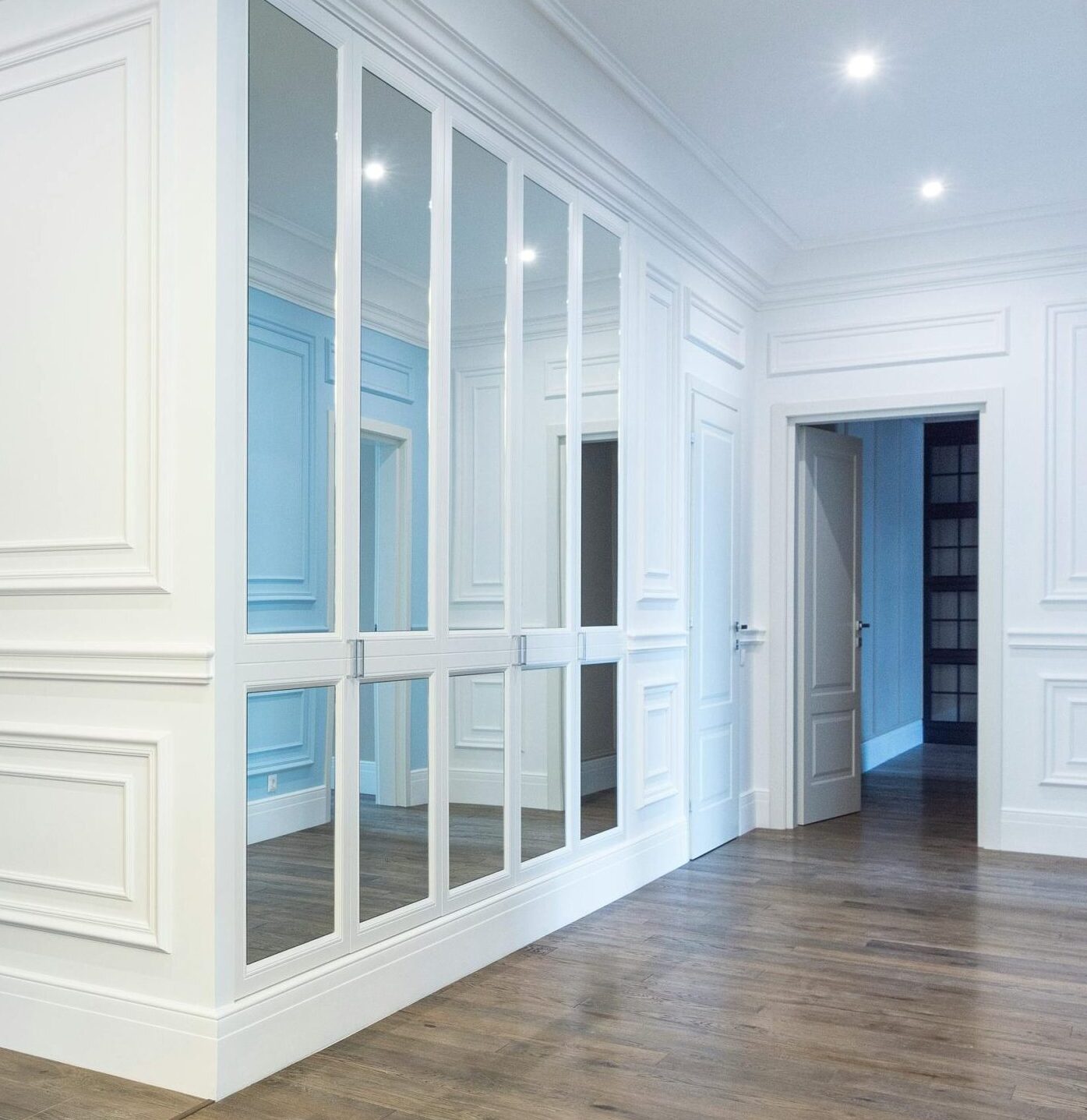 Custom mirrored wall panels and wardrobe doors installed in a modern home interior